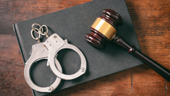 Handcuffs, gavel on book on a wooden background.