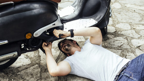 Young man having problems with the motorbike on the road